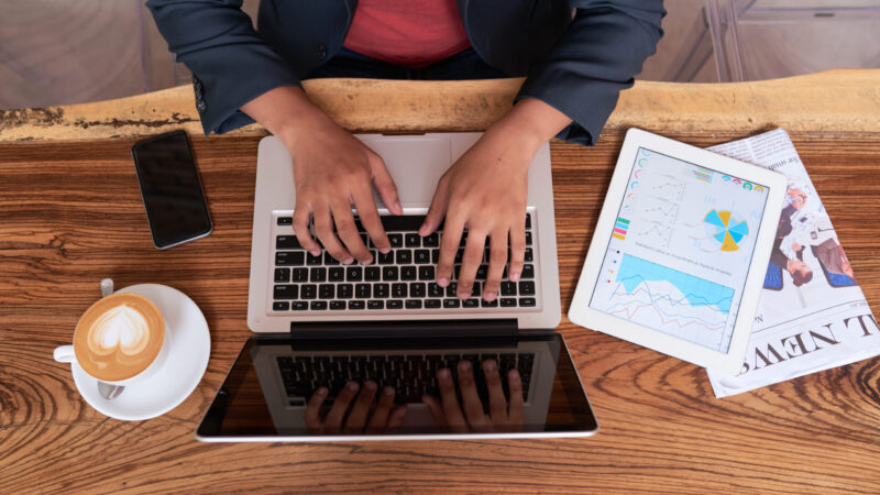 hands-unrecognizable-man-sitting-wooden-table-cafe-working-laptop